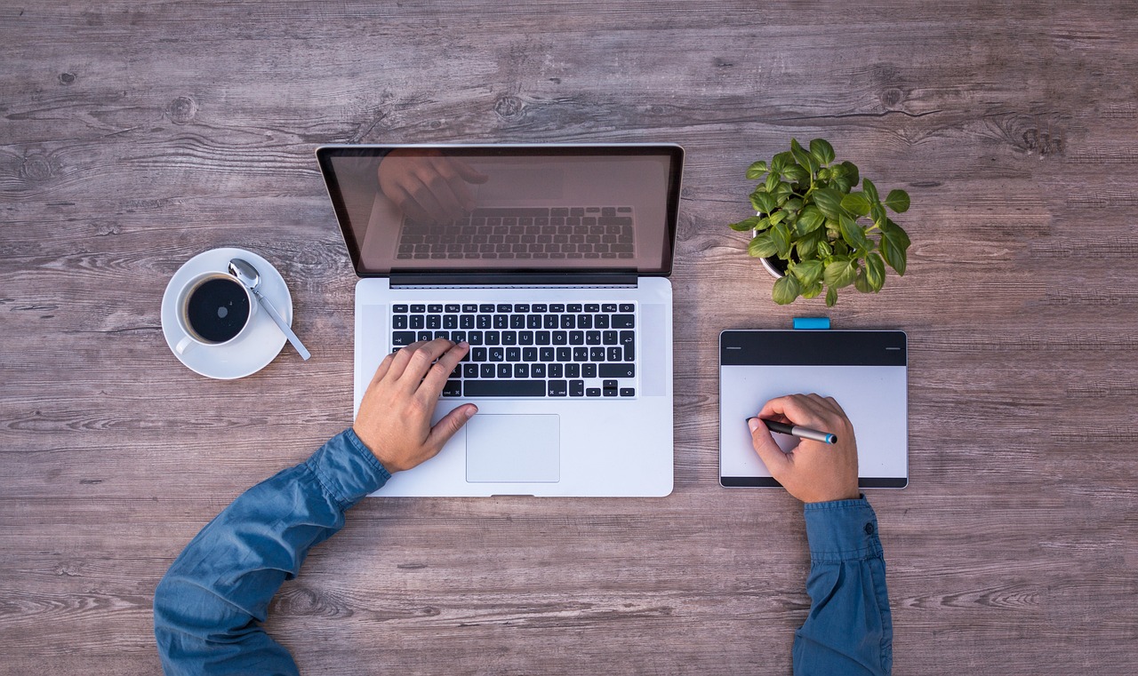 Arme die am Laptop arbeiten, Kaffeetasse, Block